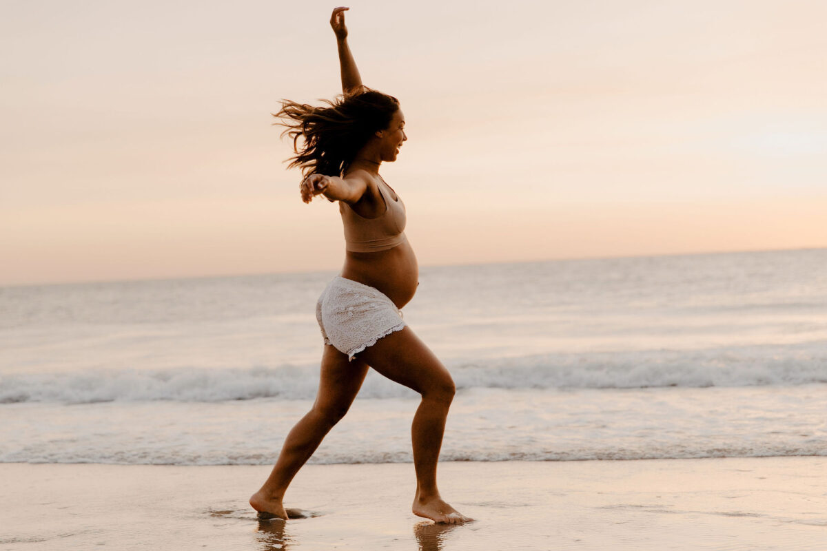 zwangere vrouw danst aan zee