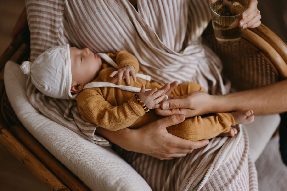 baby in armen moeder met wollen mutsje